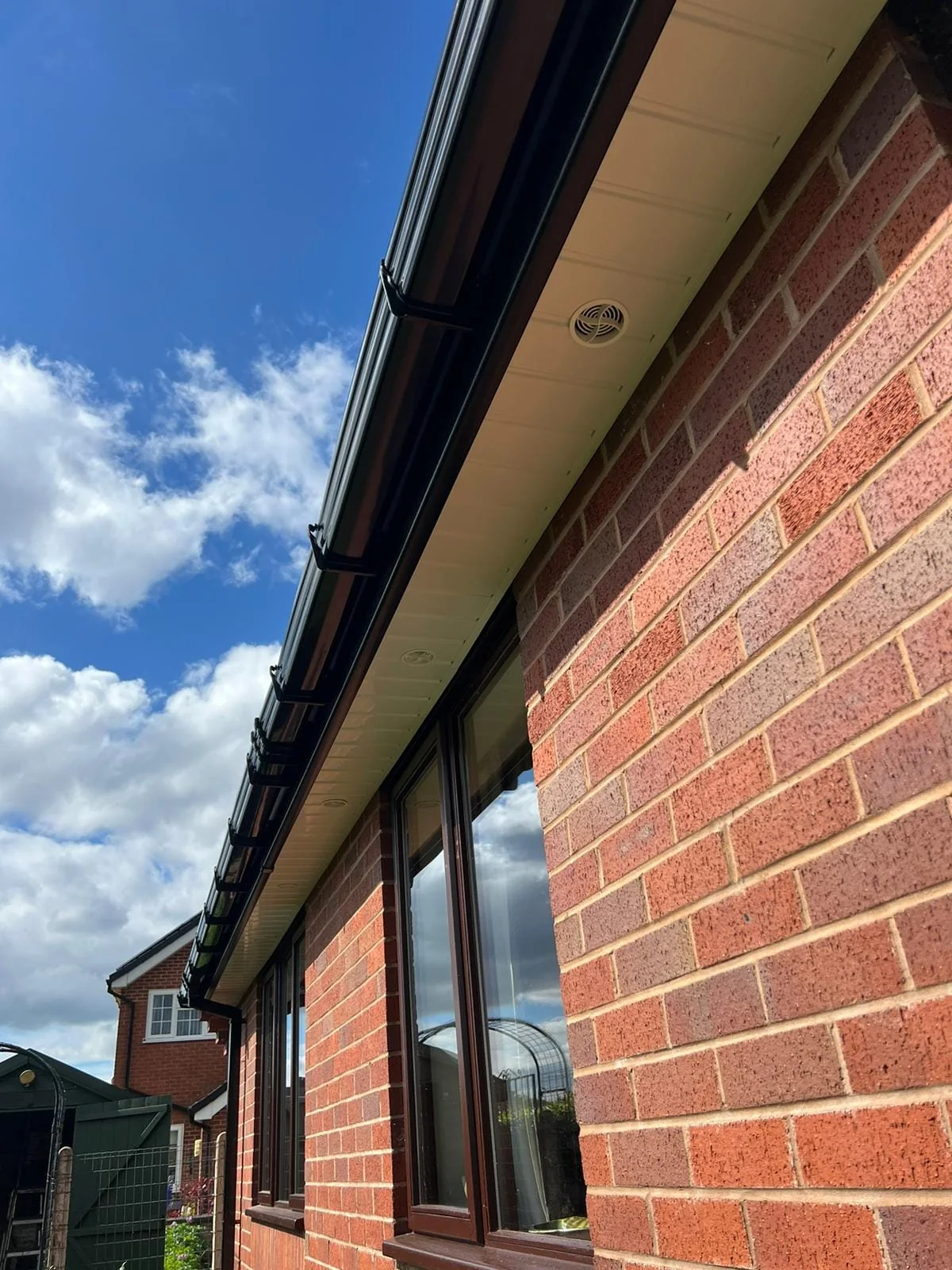 Black fascia, soffit and guttering detail beneath a tiled roof