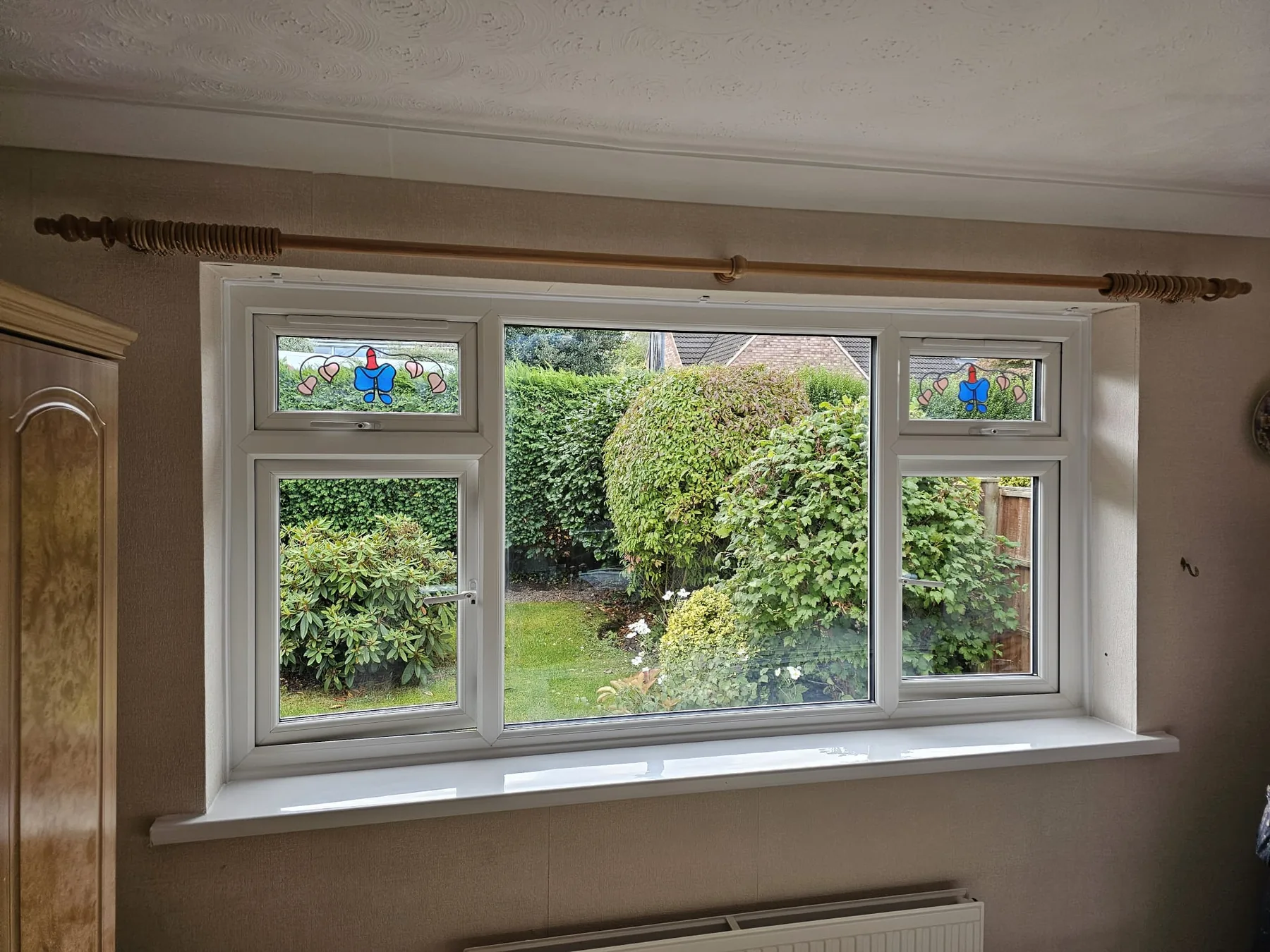 Wide white window with decorative leaded toplights and a garden view