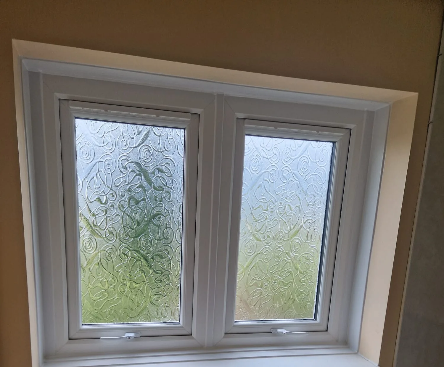 Two white casement windows with patterned privacy glass